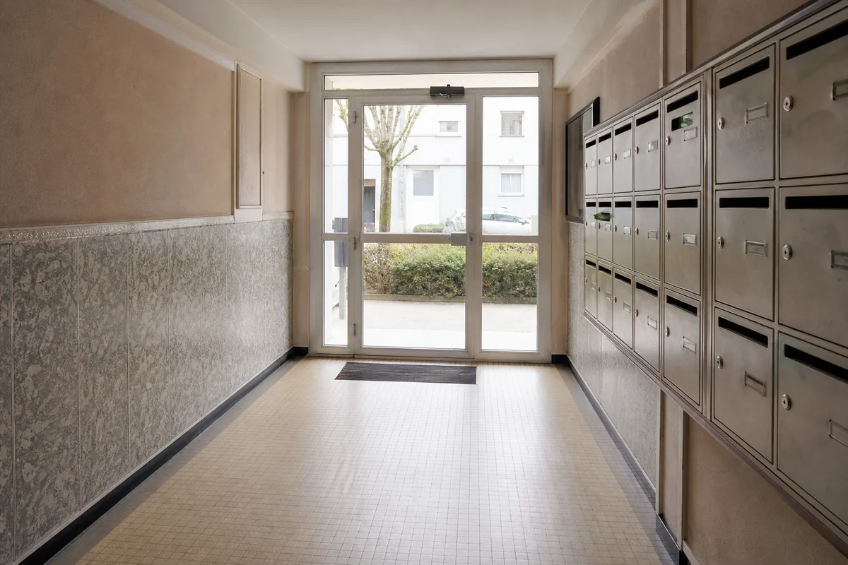 Hall d’immeuble des années cinquante à Lorient, porte vitrée et boîtes aux lettres, lumière naturelle