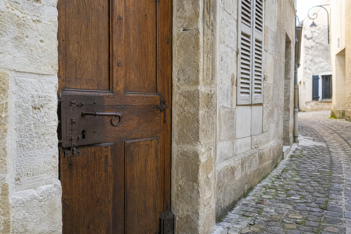 Rue pavée du centre historique de Melun, porte en bois ancienne avec serrure à gorge, lumière douce