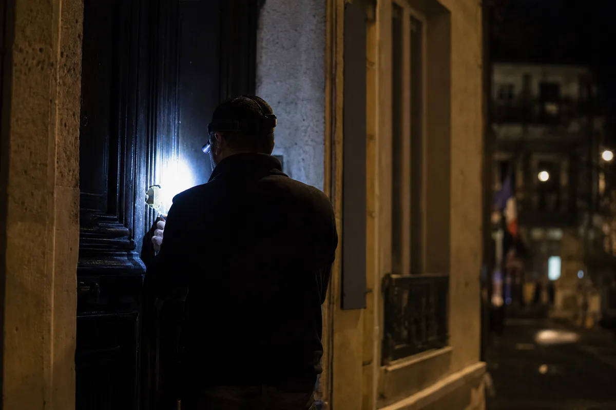 Serrurier intervenant de nuit sur une porte d’entrée d’immeuble en ville